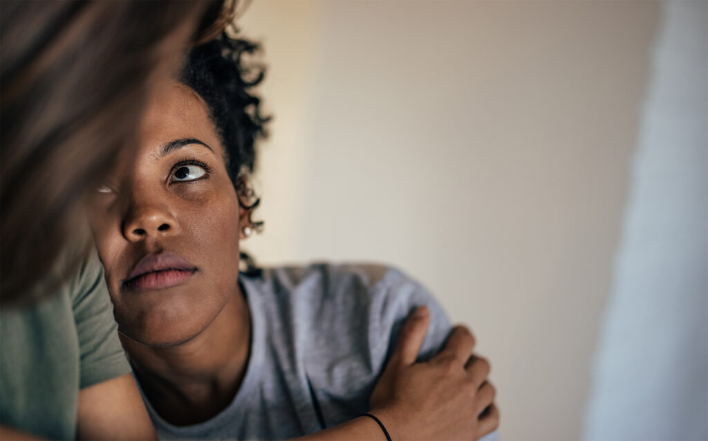 teenage girl sitting with her mother looking solemn