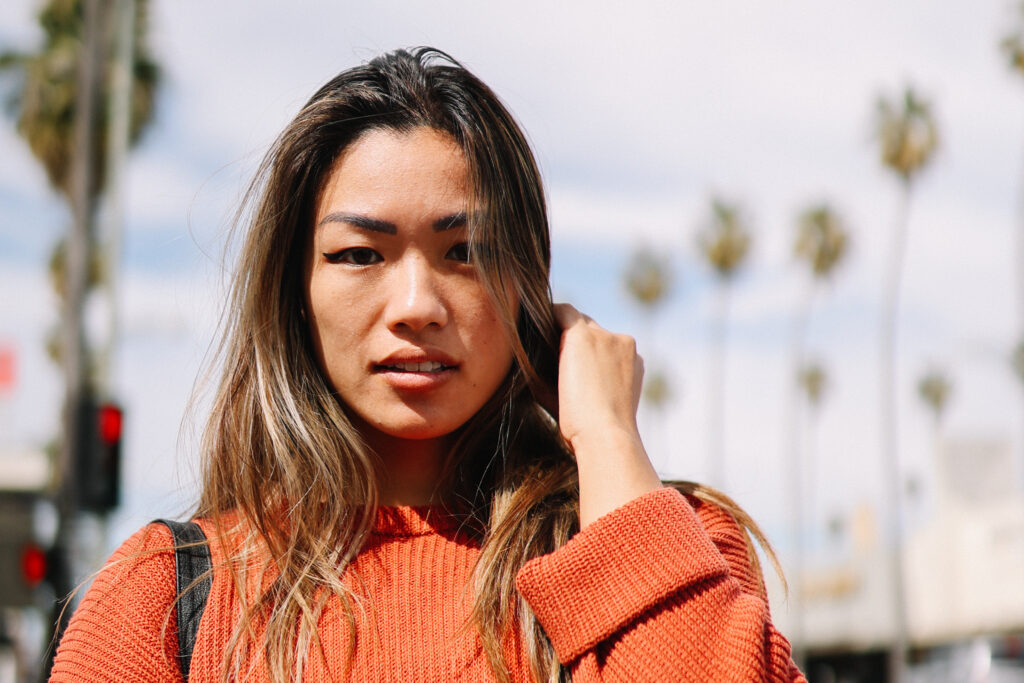 Young woman faces the camera head on with palm trees in the background, representing a human trafficking survivor or advocate
