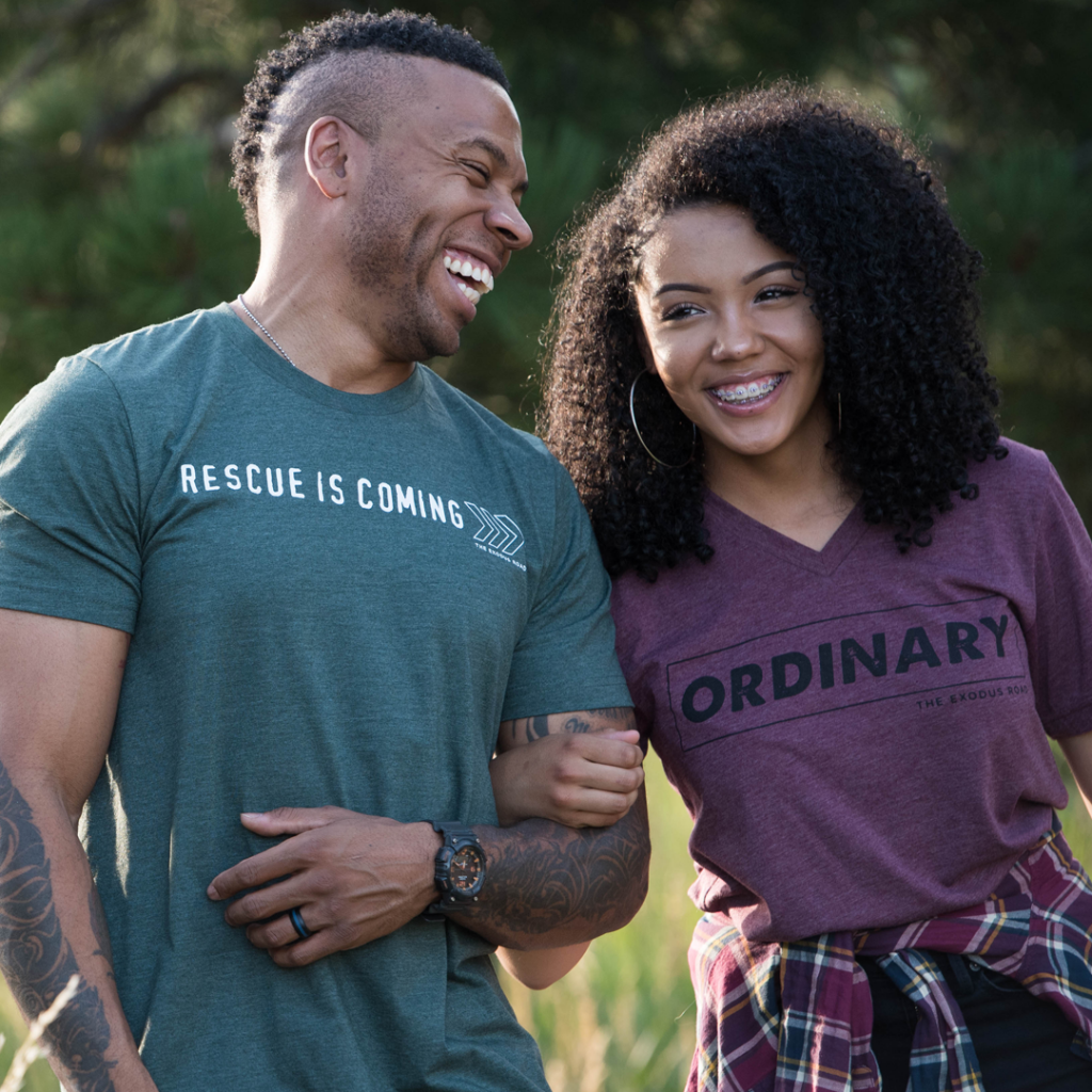 an African American man and woman link arms wearing The Exodus Road t-shirts, representing the ways to fight human trafficking are things everyone can join in