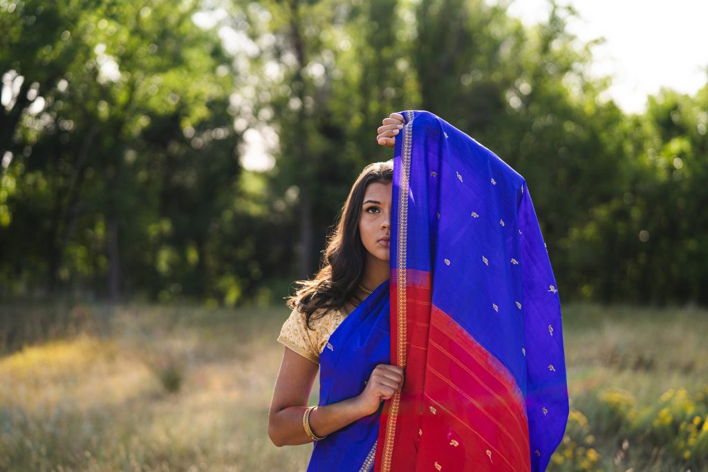 Young Indian girl stares straight ahead with saree covering half of her face.
