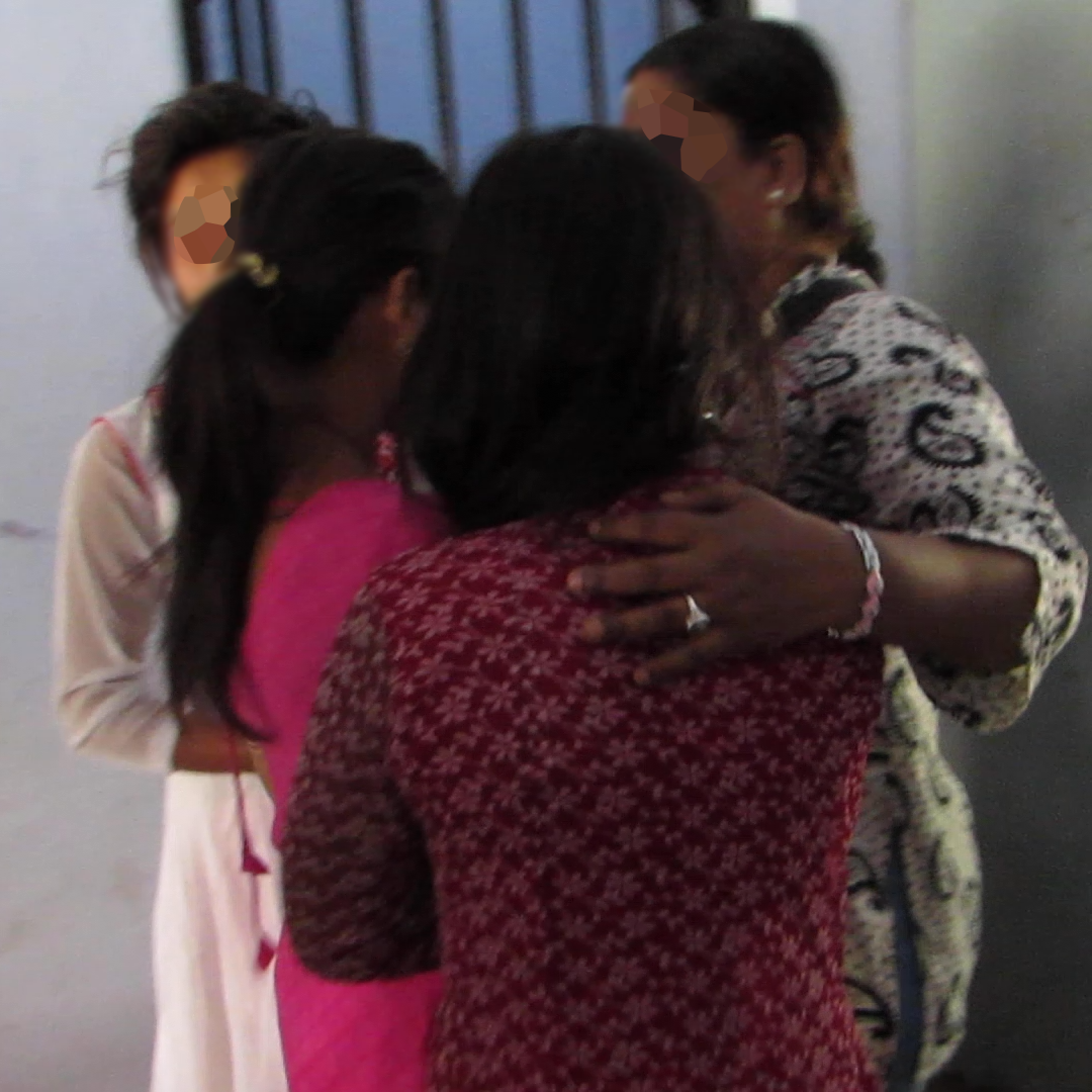 Una trabajadora social en la India consuela a tres mujeres jóvenes sobrevivientes de la trata de personas.