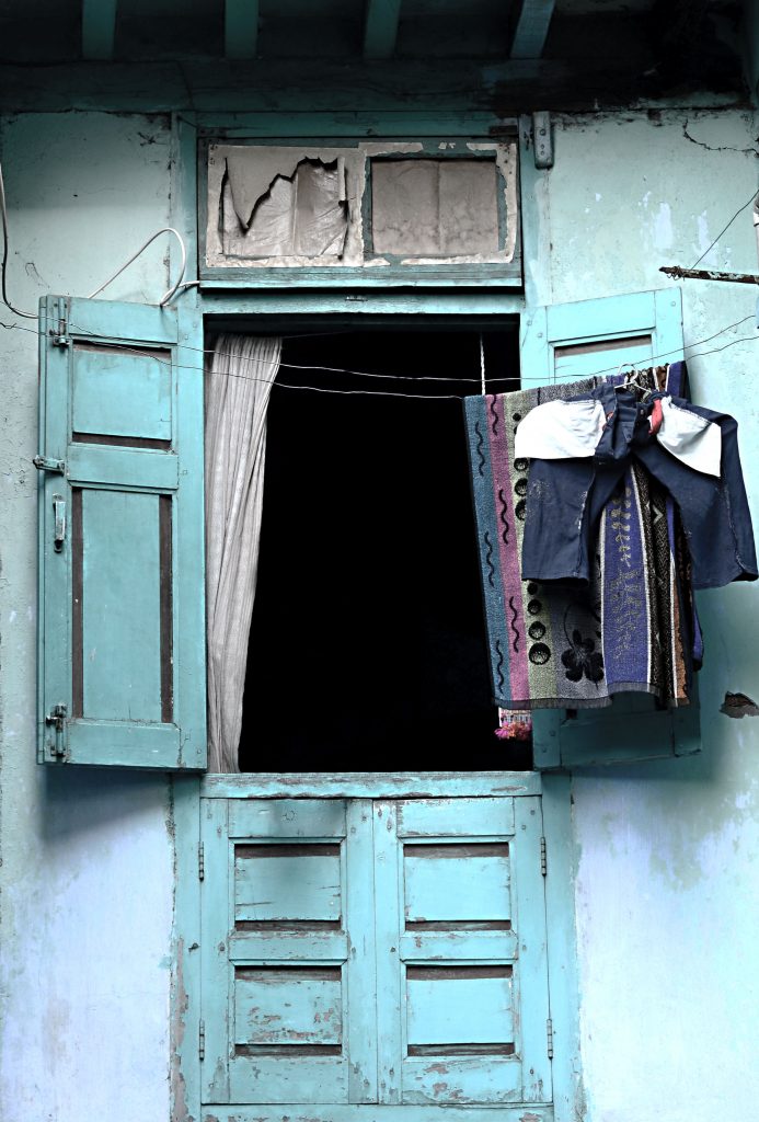 Blue door with shutters opened and laundry hanging on a line.