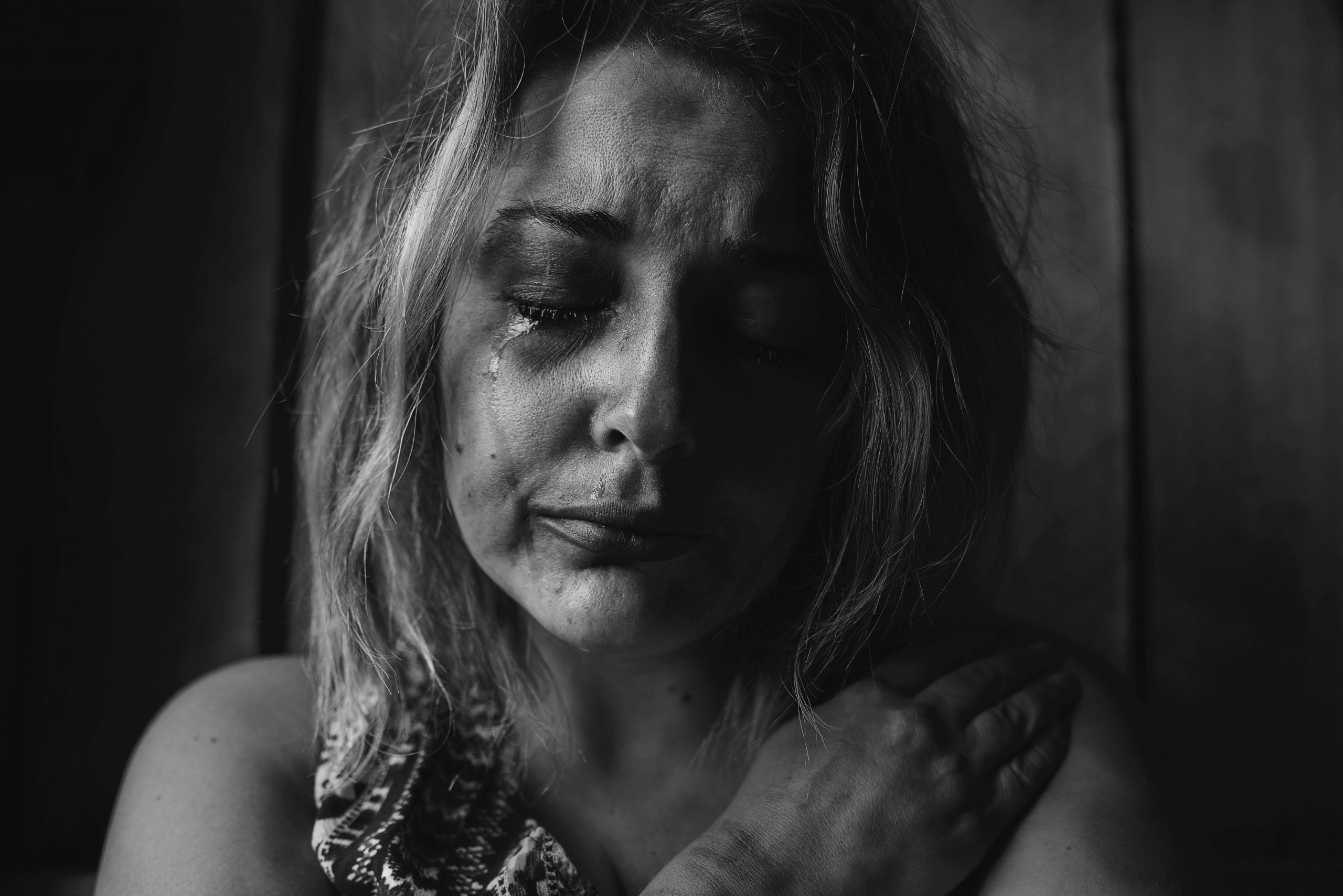 A close-up black and white image of a woman crying.
