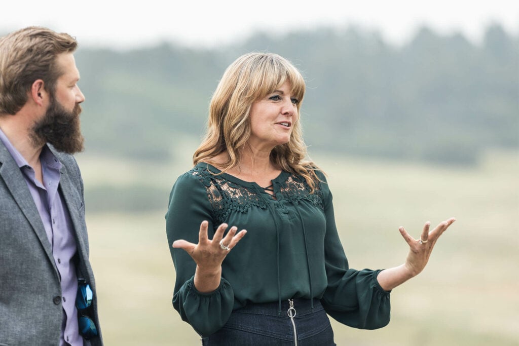 Laura Parker, CEO and Co-Founder of The Exodus Road, stands speaking at an outdoor event.