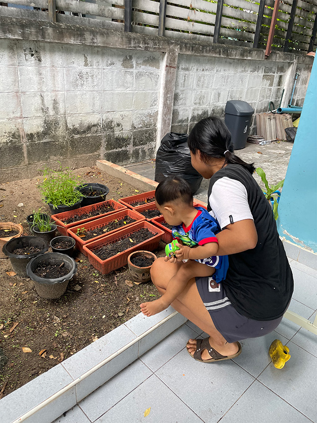 cliente de The Exodus Road's Freedom Home en Tailandia con su hijo trabajando en el jardín comunitario