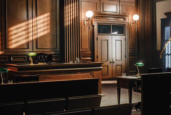 Empty courtroom with light shining in through windows at right of scene.