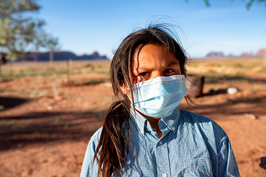 young Native American girl wearing a face mask standing in a desert landscape