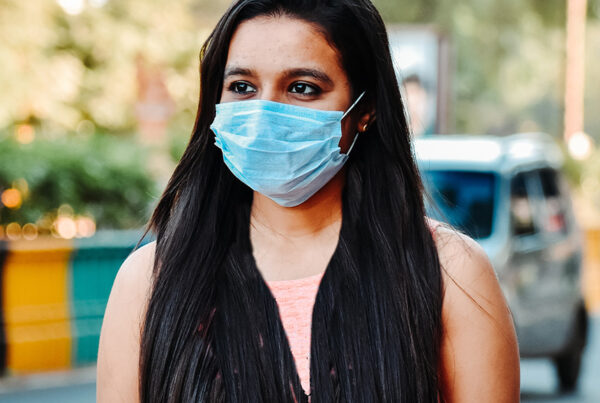 मास्क पहने मुस्कुराती युवा भारतीय महिला