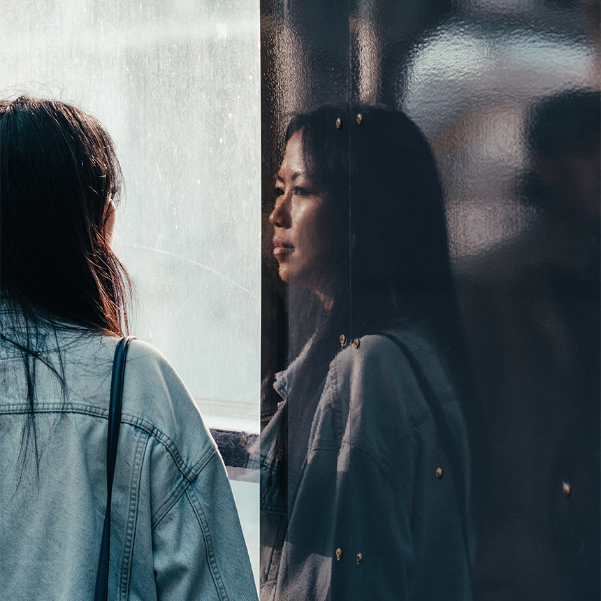 young woman looking at her reflection, representing the need for survivors of trafficking to receive trauma-informed aftercare as they heal from their exploitation
