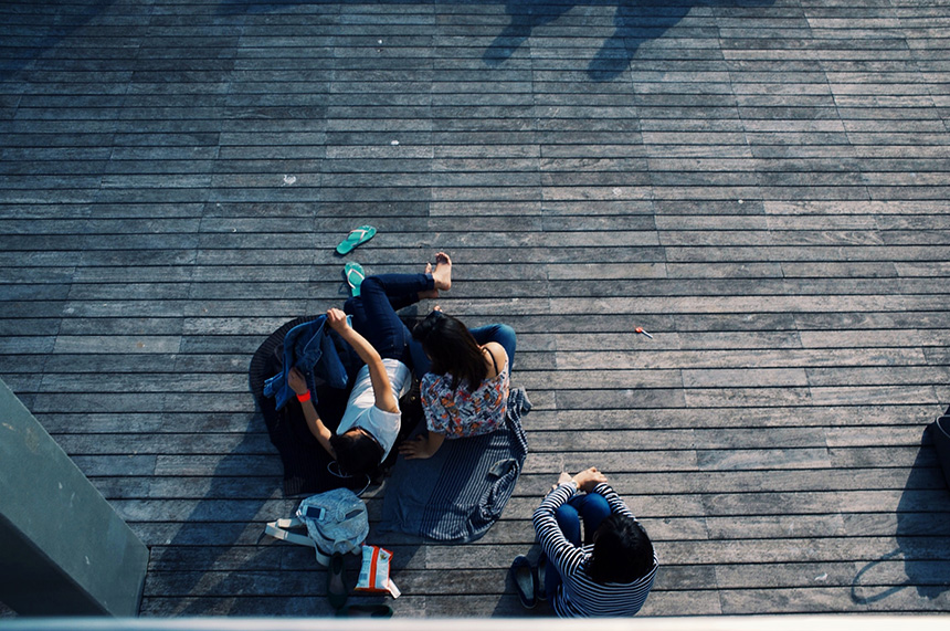 Overhead image of a group of teenagers sitting outside together.