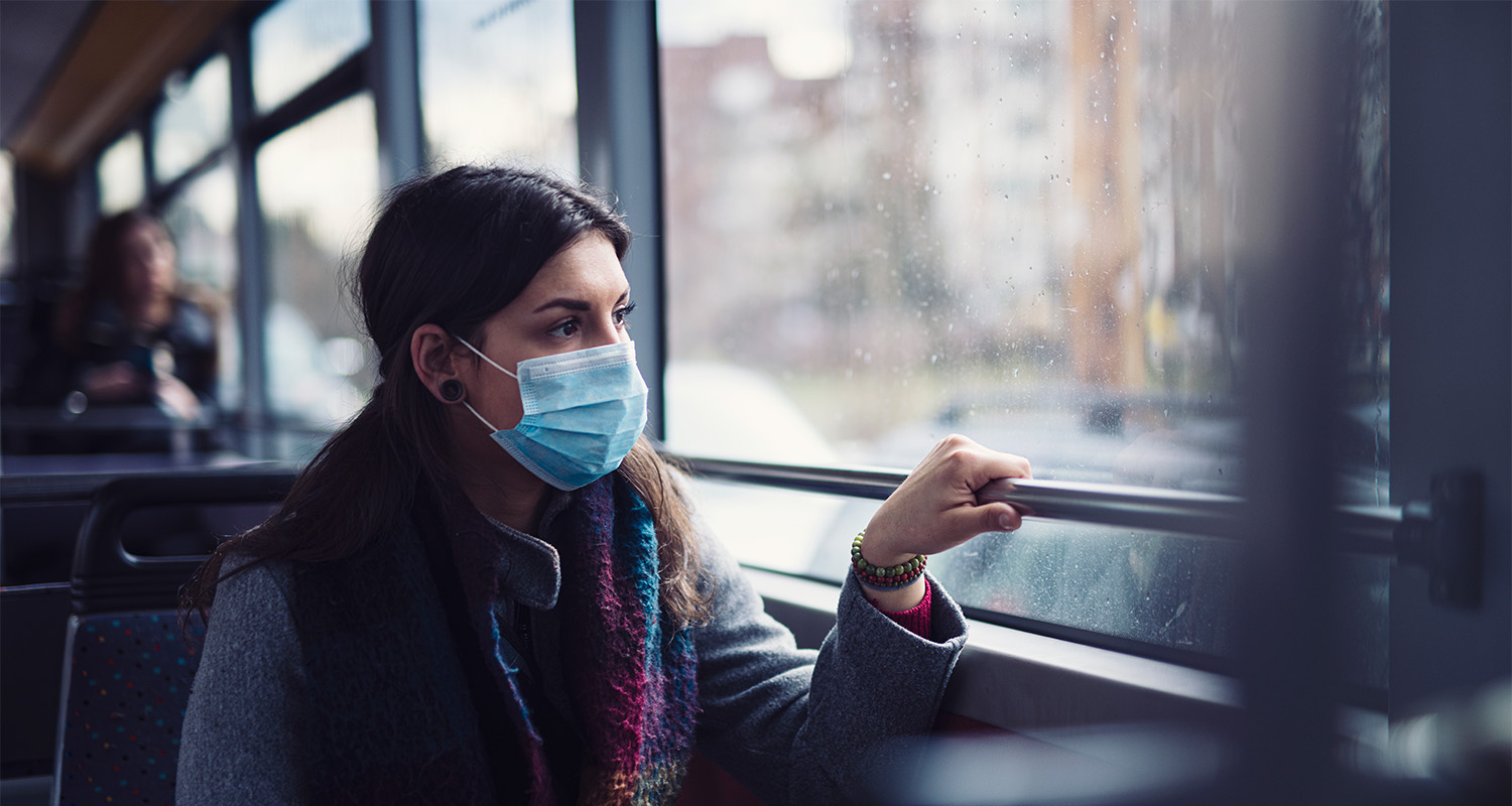 young woman wearing a mask riding a public bus