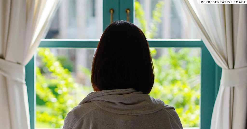 young Thai girl sitting looking out a window
