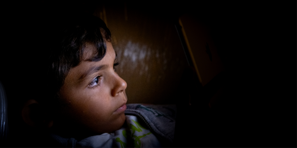 Boy looking at a screen in a dark room