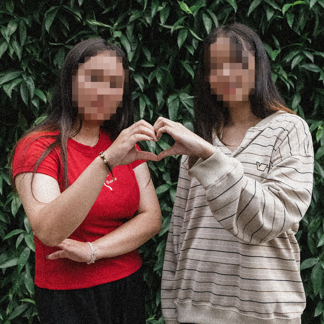 Two survivors of sex trafficking make a heart with their hands