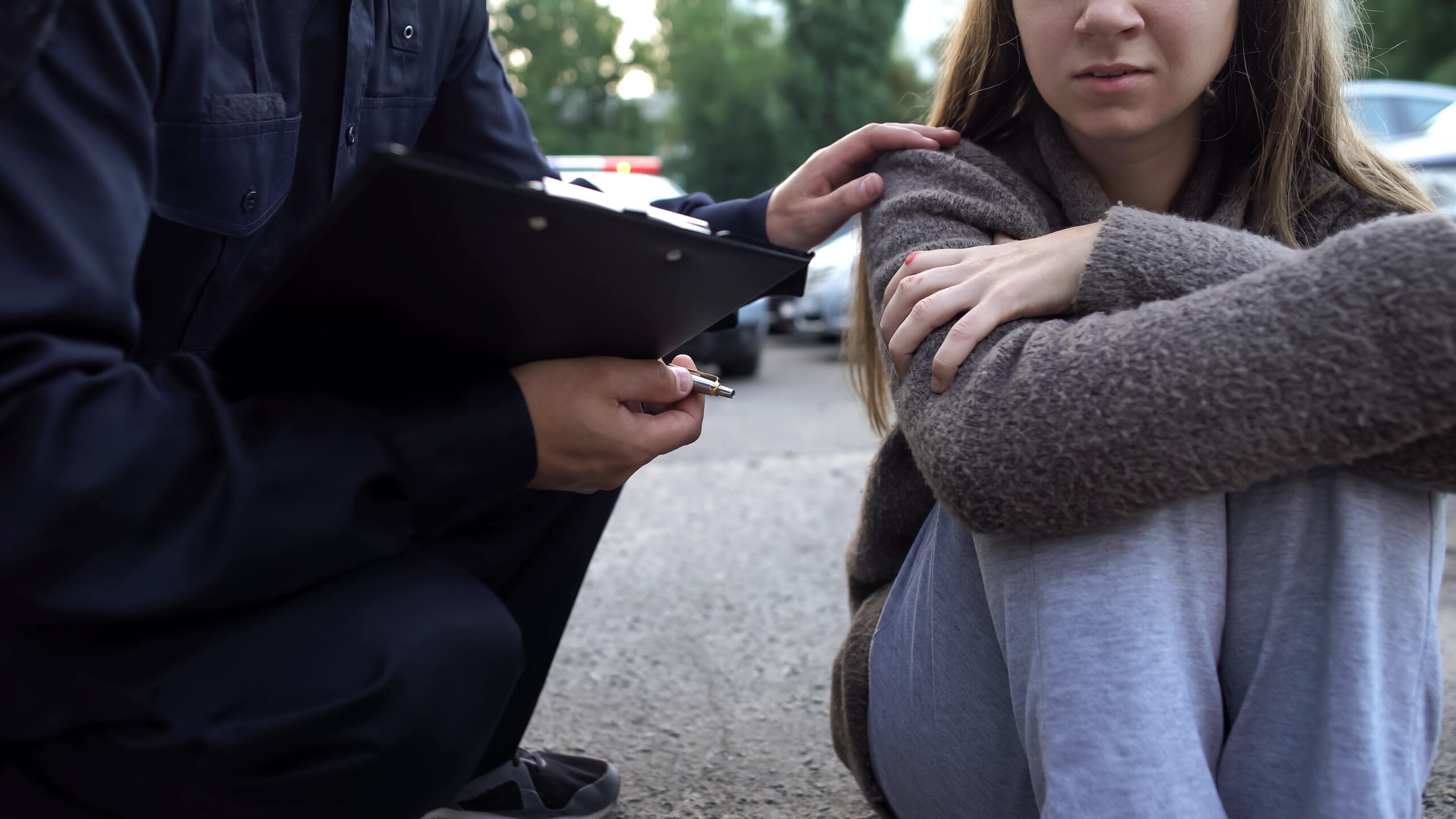 Police officer rests a hand on the shoulder of a distressed your woman