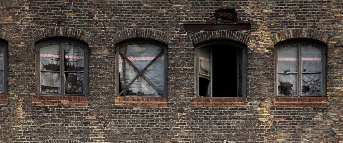 Run down brick building with open window.