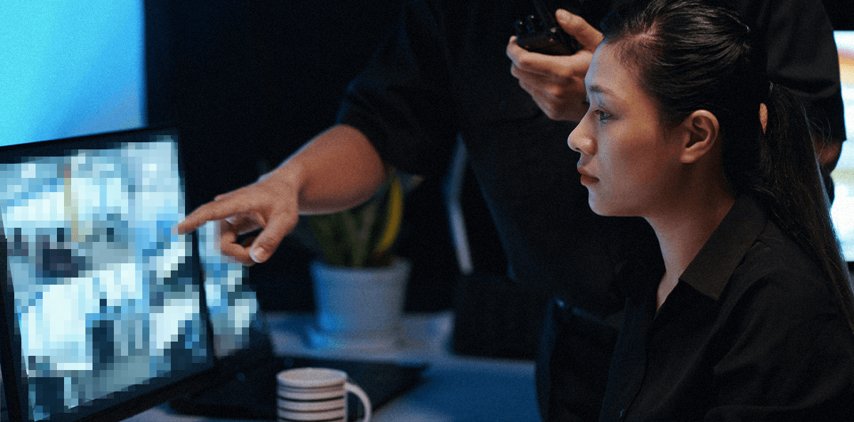 two asian investigators look at a computer together. The computer screen is pixelated.