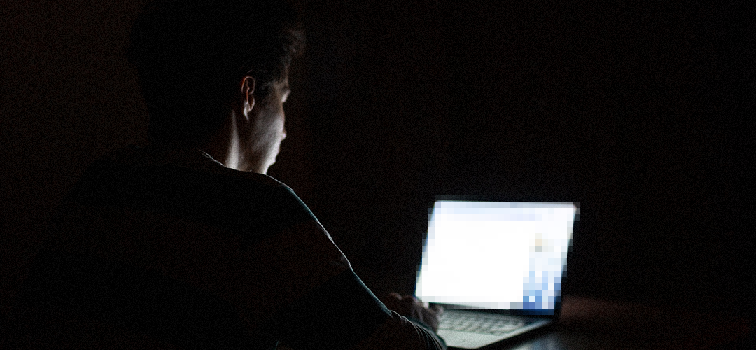 Man on computer in the evening. The computer screen is pixelated.