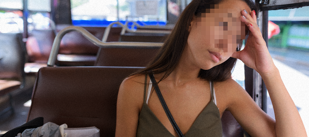 Young asian woman with a hand on her head, travels by bus, looking out window.