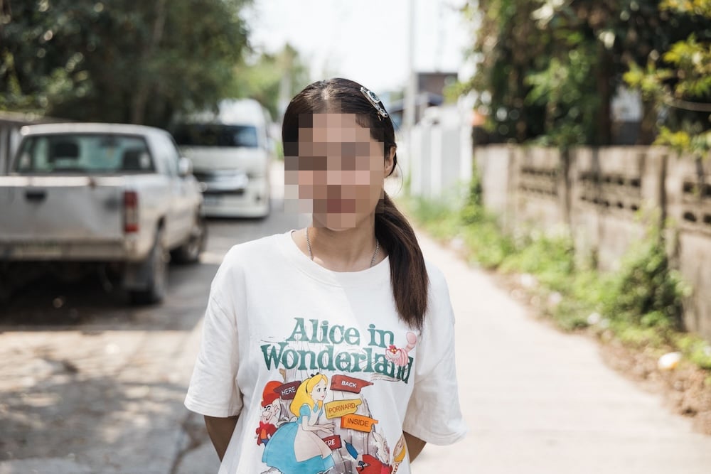 A survivor stands outside her home in Thailand