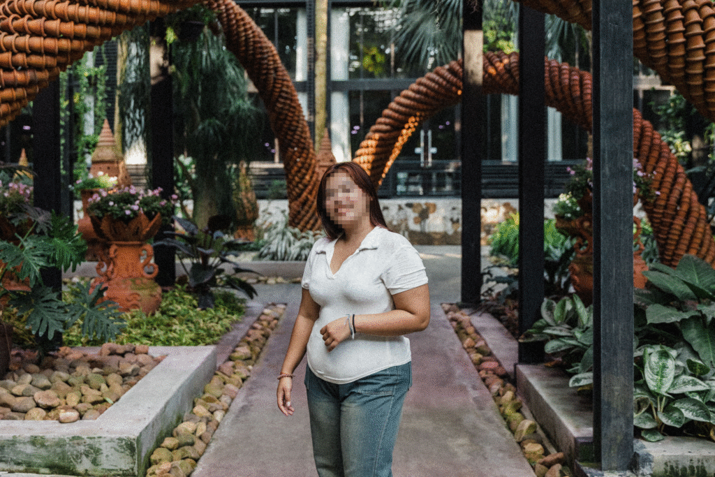Aree, a survivor of sex trafficking, stands in a garden while smiling