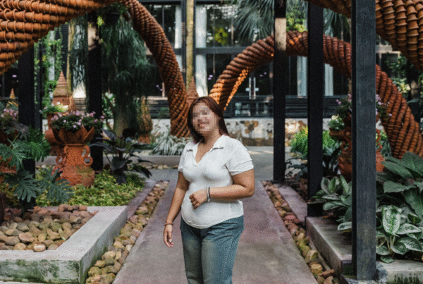 Aree, a survivor of sex trafficking, stands in a garden while smiling