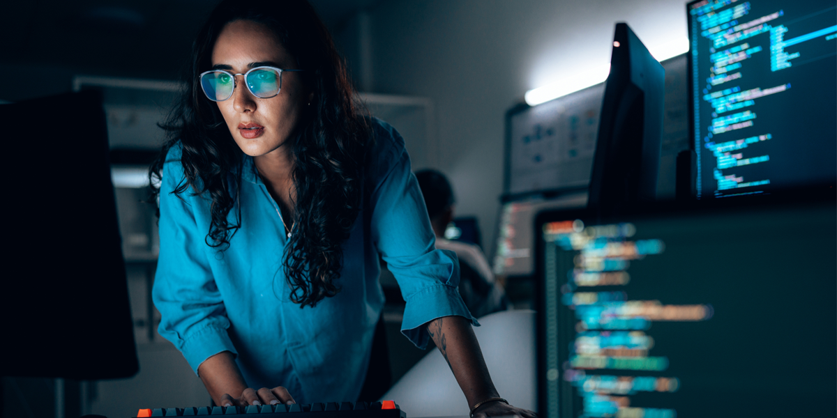 A woman surrounded by computer screens analyzing data