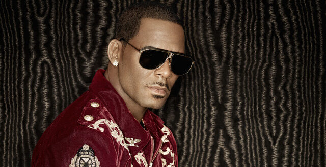 R&B artist R. Kelly wearing sunglasses and a red embroidered jacket