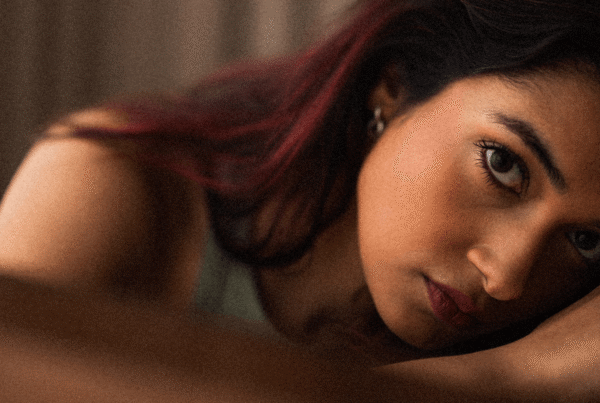 Young woman from India looks up at camera with a somber expression and her head in her lap.