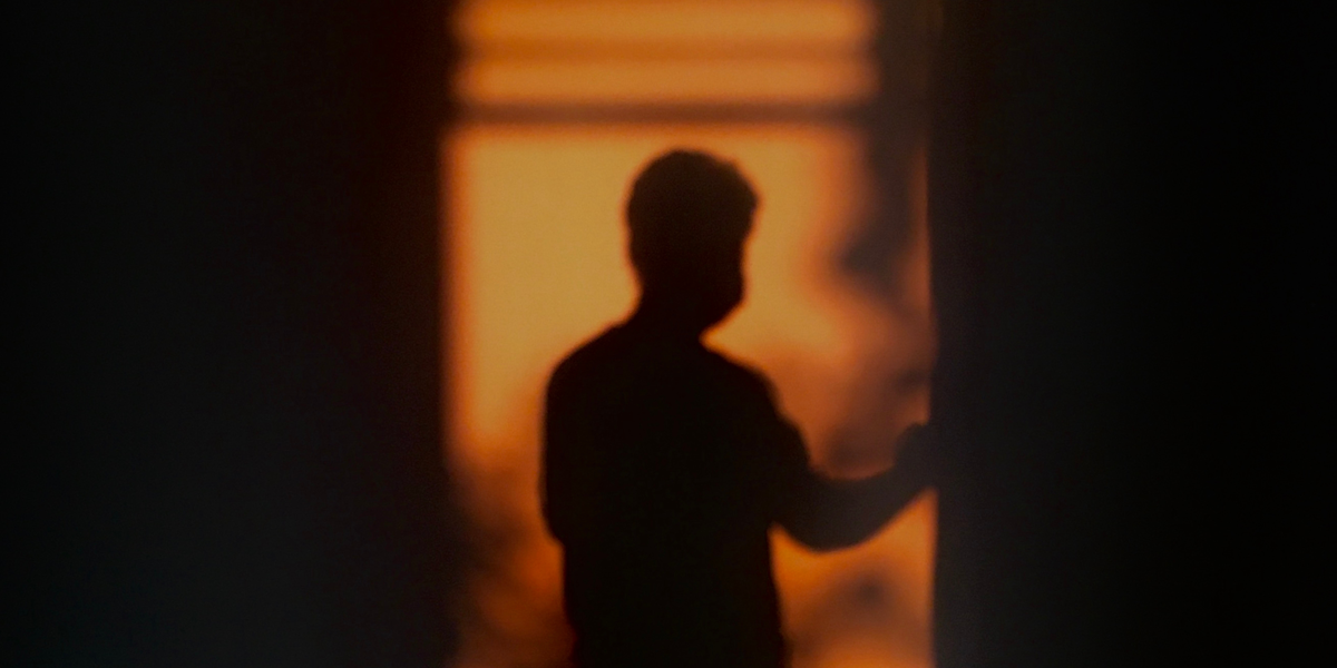Warm silhouette of a man by a window with blinds