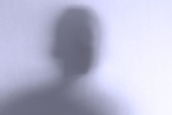 Defocused face behind a white glass background