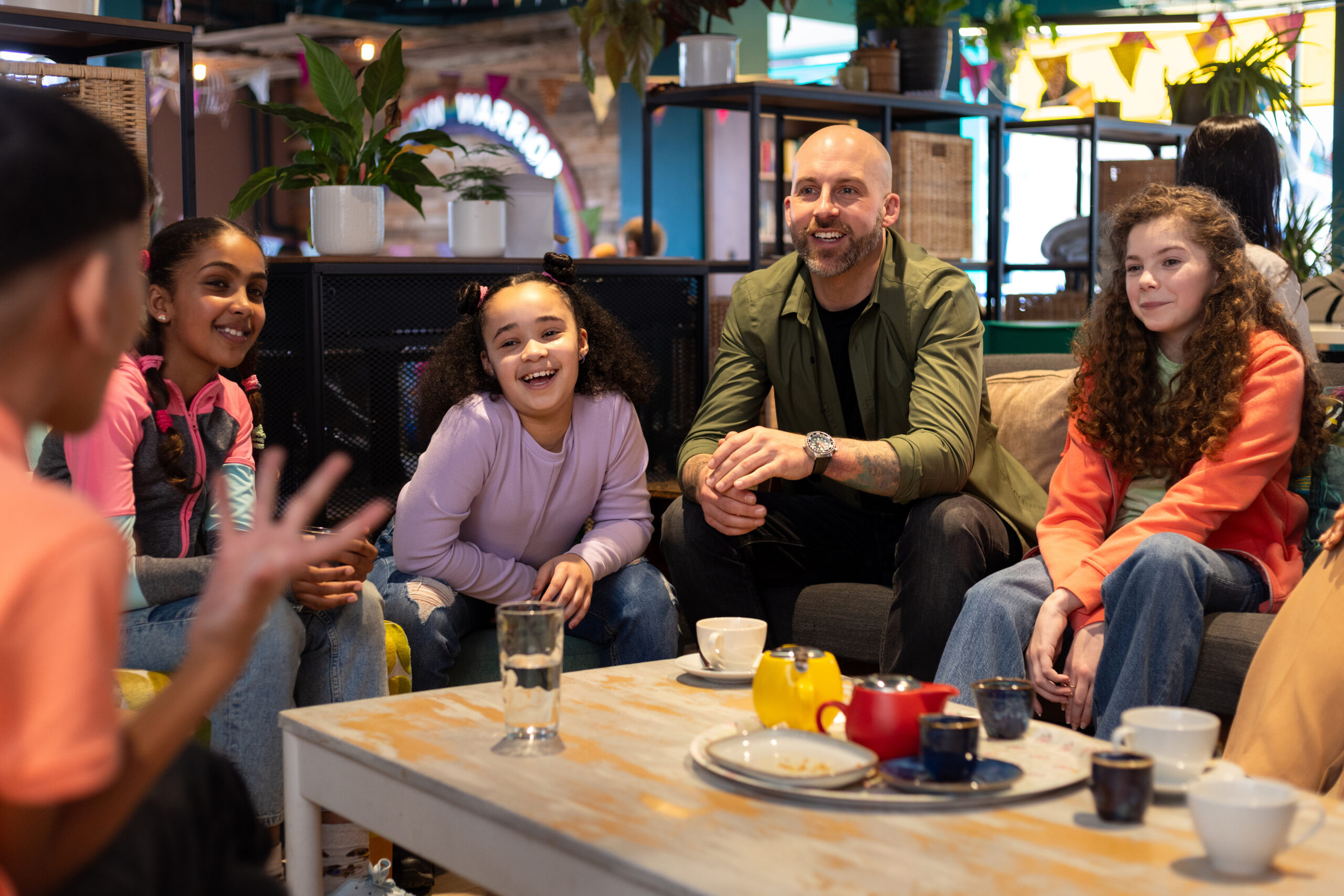 A youth leader sits with a small group of kids in a community space.