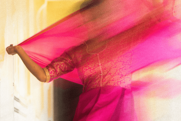 Blurred image of an Indian young woman dancing in pink traditional clothing.