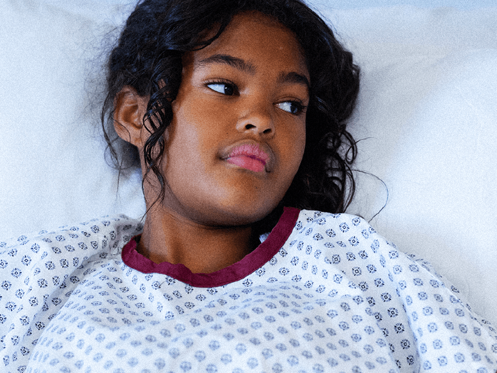 young biracial girl lays in a hospital bed