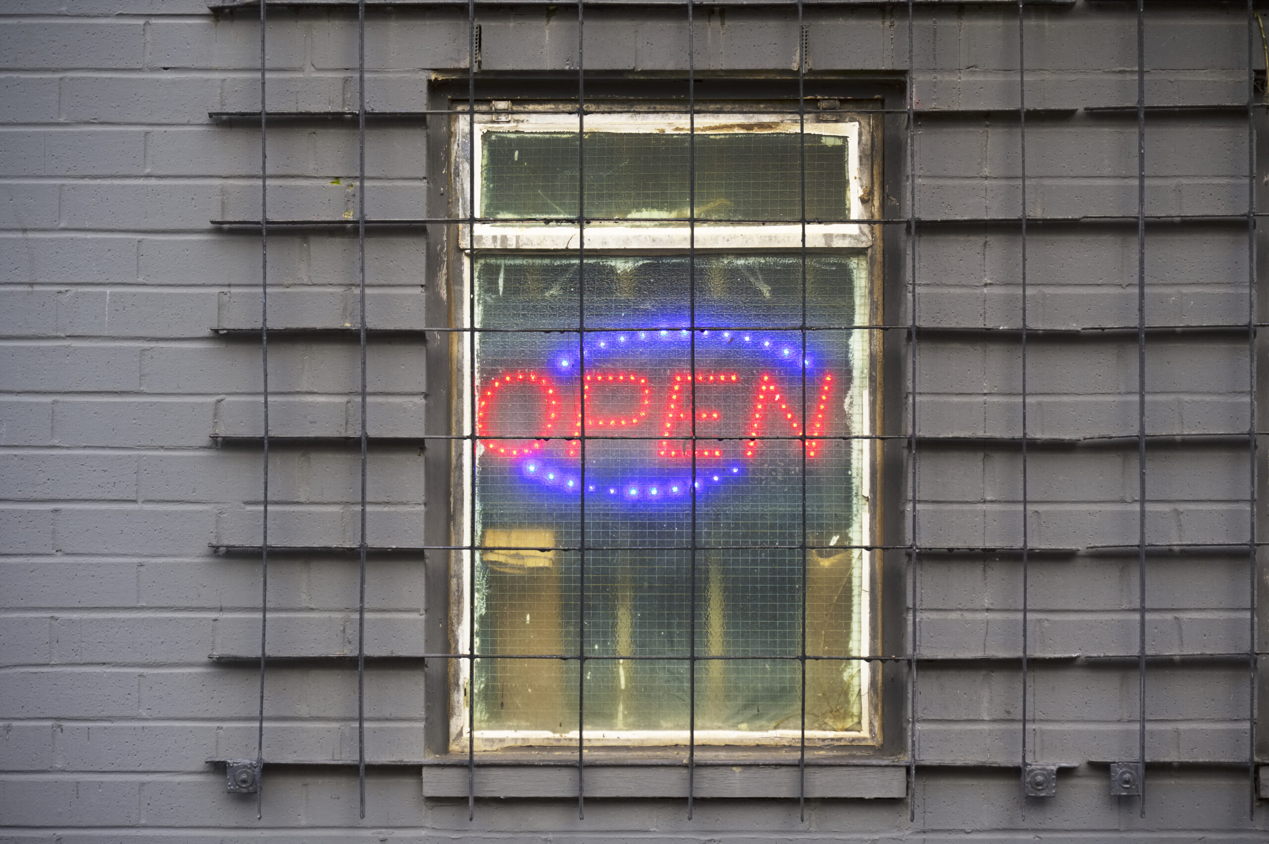 Open sign in a barred window representing an illegal massage business