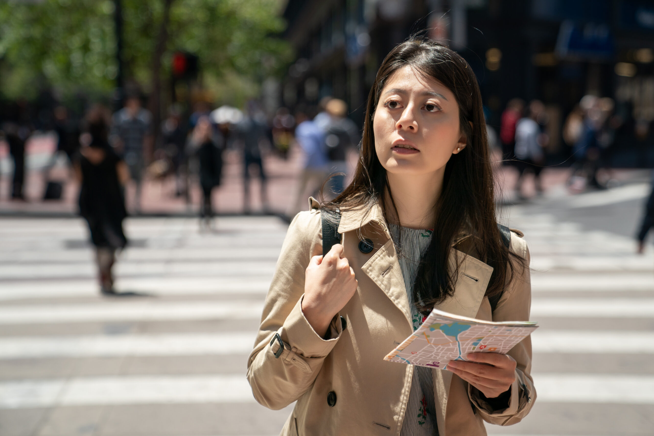 Asian woman holding a map on a crosswalk in America