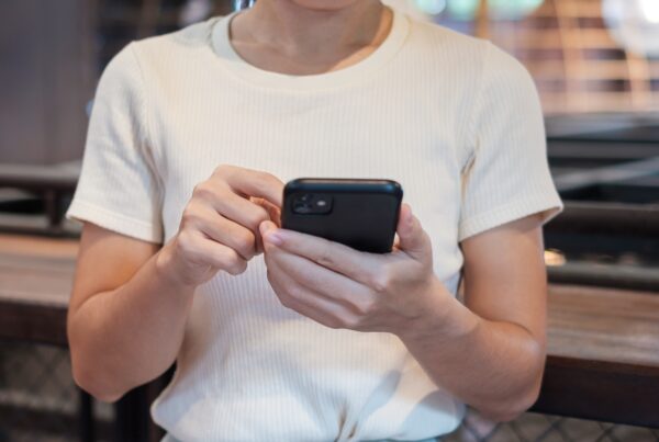 Young business woman using a black smartphone, representing someone scrolling through potentially false job offers