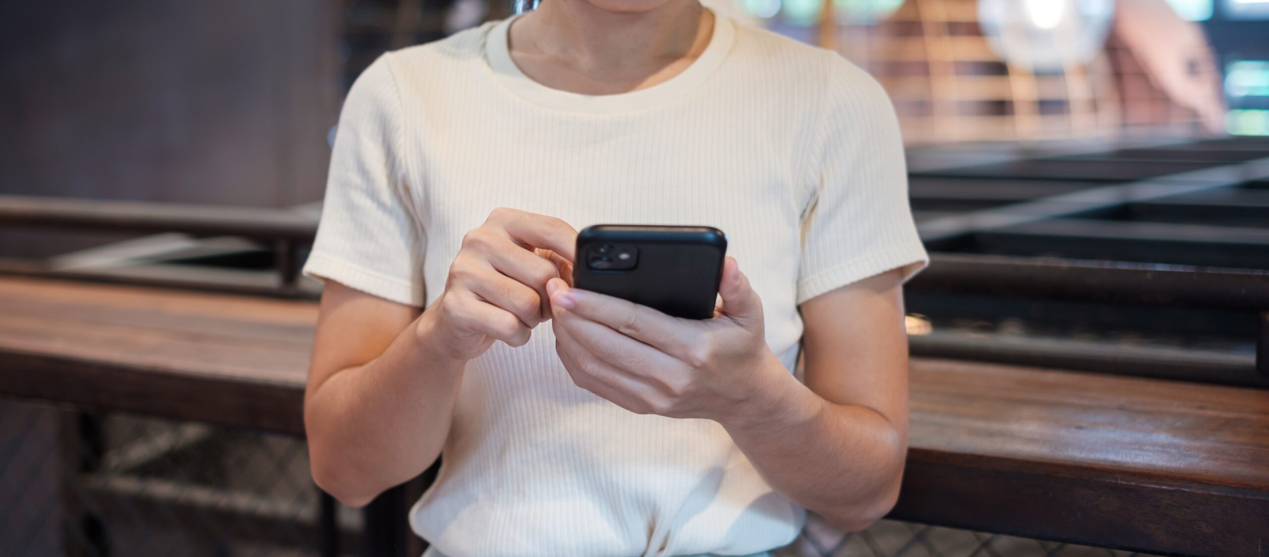 Young business woman using a black smartphone, representing someone scrolling through potentially false job offers