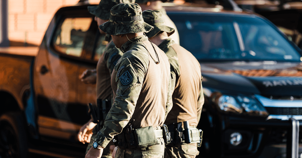 Law enforcement officers walk outdoors by a cop car in Latin America