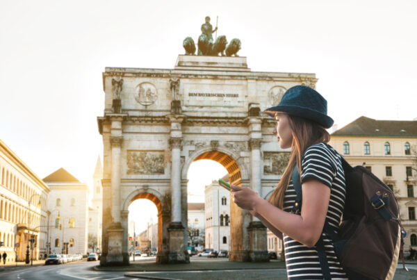 A tourist girl with a backpack looks sights in Munich in Germany. Passes by the triumphal arch.